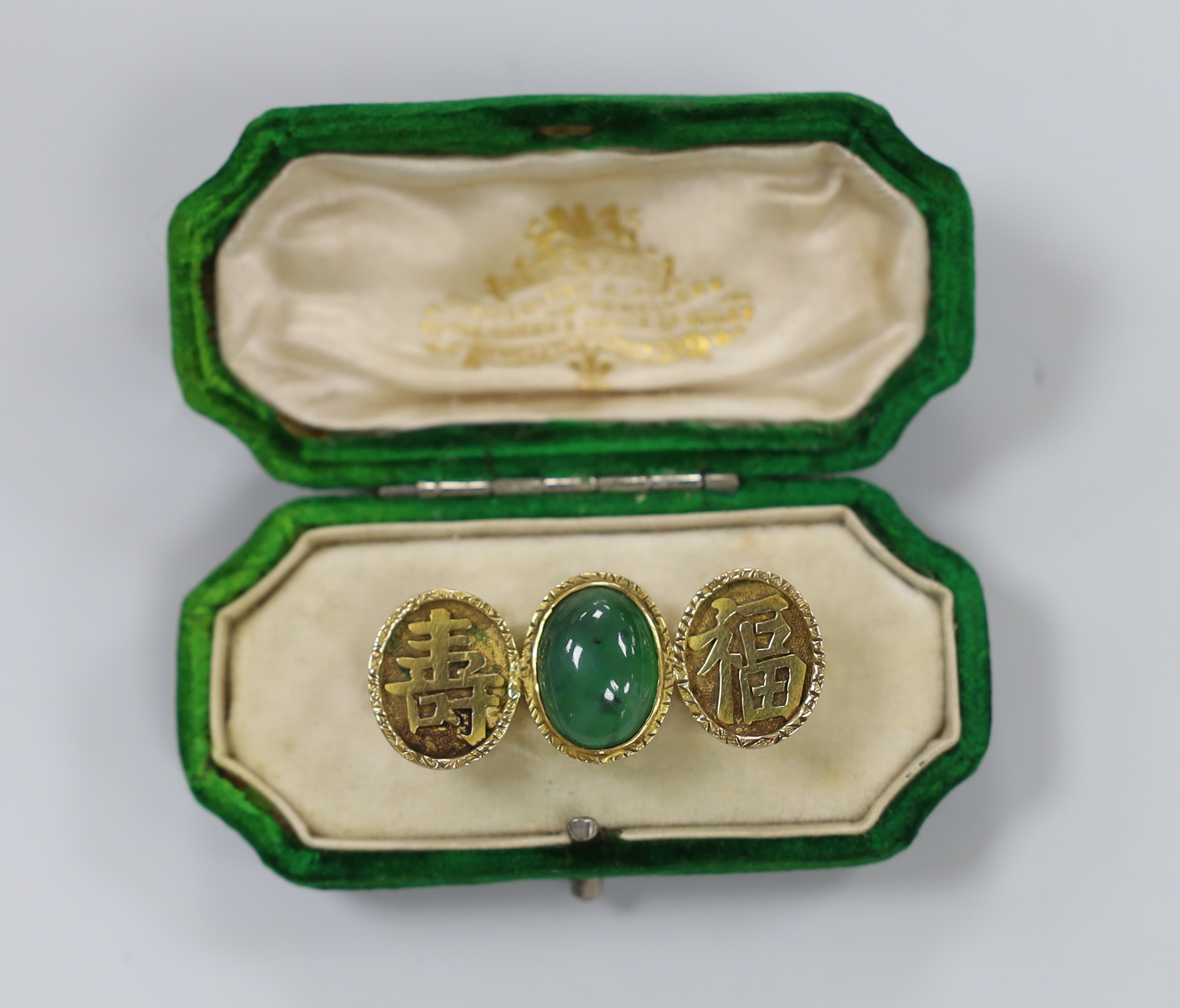 A Chinese yellow metal and cabochon jade and Chinese character set triple oval motif brooch, 39mm, gross weight 6.2 grams.